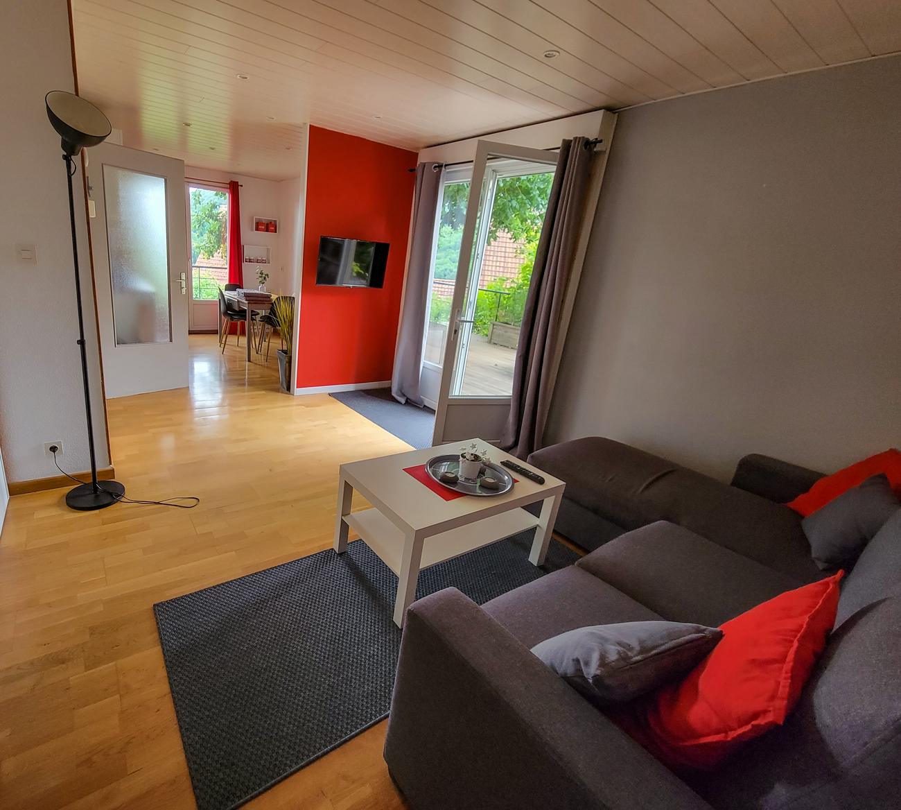 Séjour avec canapé 4 places convertible, télévision et porte-fenêtre sur la terrasse